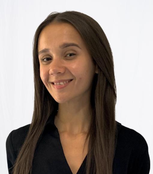 Donelle - headshot of young person smiling with long brown hair wearing a black top.