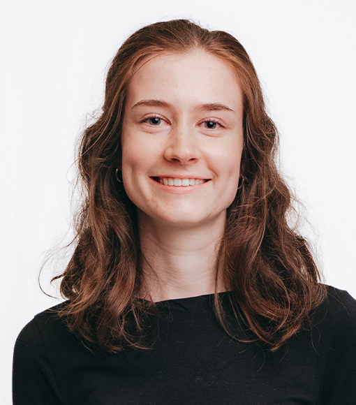 Emily - headshot of smiling young person with shoulder length reddish brown hair wearing a black jumper