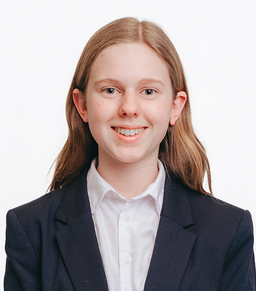 Isabel - headshot of a smiling young person with long blonde hair wearing a white collared shirt and navy blue blazer.