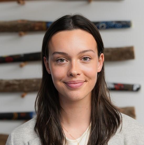 Headshot of Isabella. A young person with long brown hair wearing a light coloured tshirt.