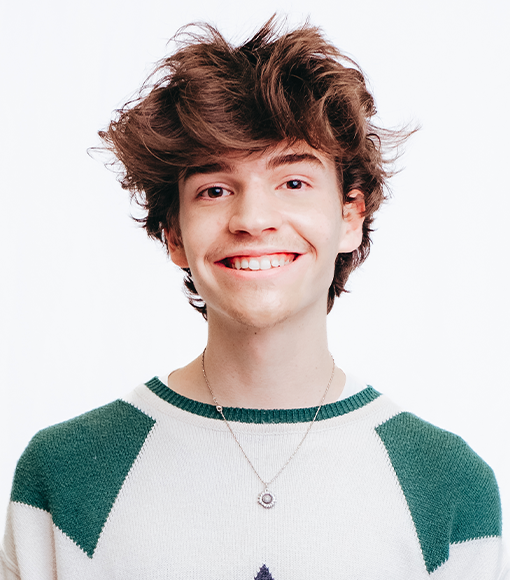 Jet - headshot of a smiling young person with short brown hair wearing a white and green jumper and a sliver pendant