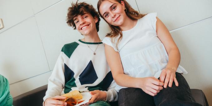 Two young people smiling and eating lunch.