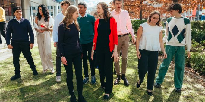 A group of young people standing together smiling on grass