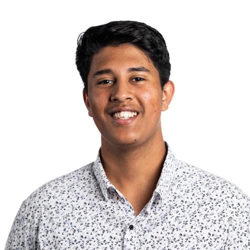 Image of Adriel smiling at the camera with short hair and a collared shirt.