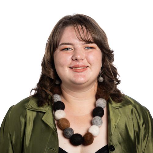 Head shot of Emma smiling at the camera with shoulder length hair, wearing a satin collared shirt.
