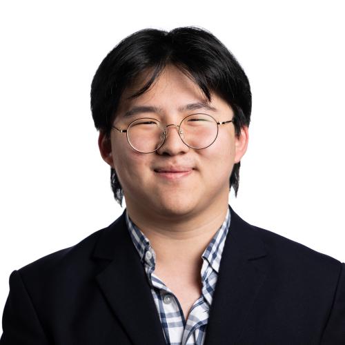 Image of Gavyn with short, straight hair wearing spectacles, a collared shirt and blazer.
