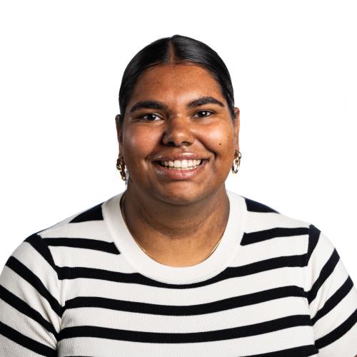 Image of Kelsee smiling with her hair tied back, wearing gold earrings and a t-shirt.
