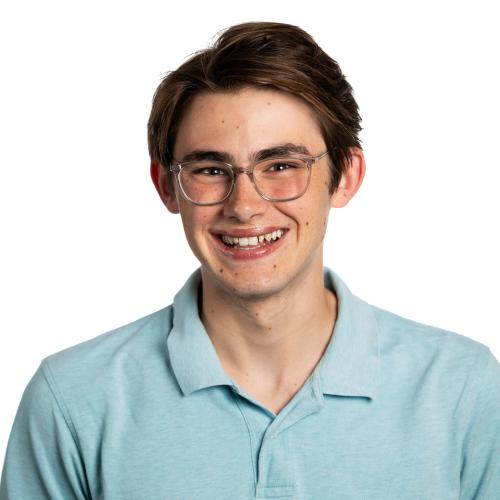 Image of Kuba smiling at the camera, wearing glasses and a collared shirt.