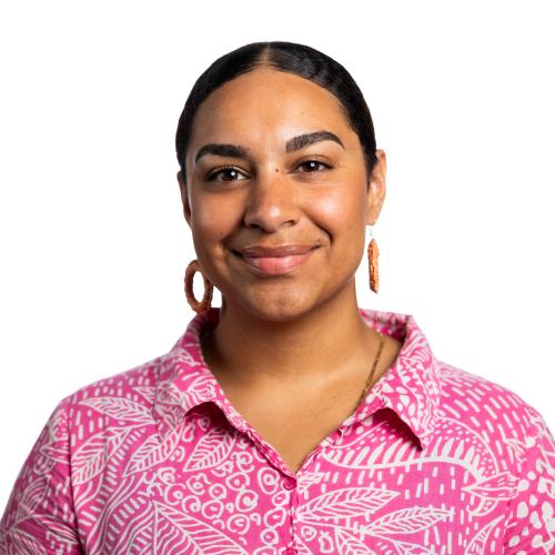 Image of Rikisha smiling with her hair tied back, wearing hoop earrings and a collared shirt.