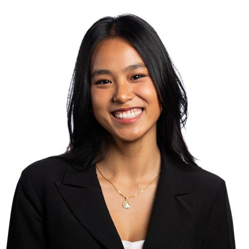 Image of Suriana smiling with shoulder length straight hair wearing a jacket and t-shirt.